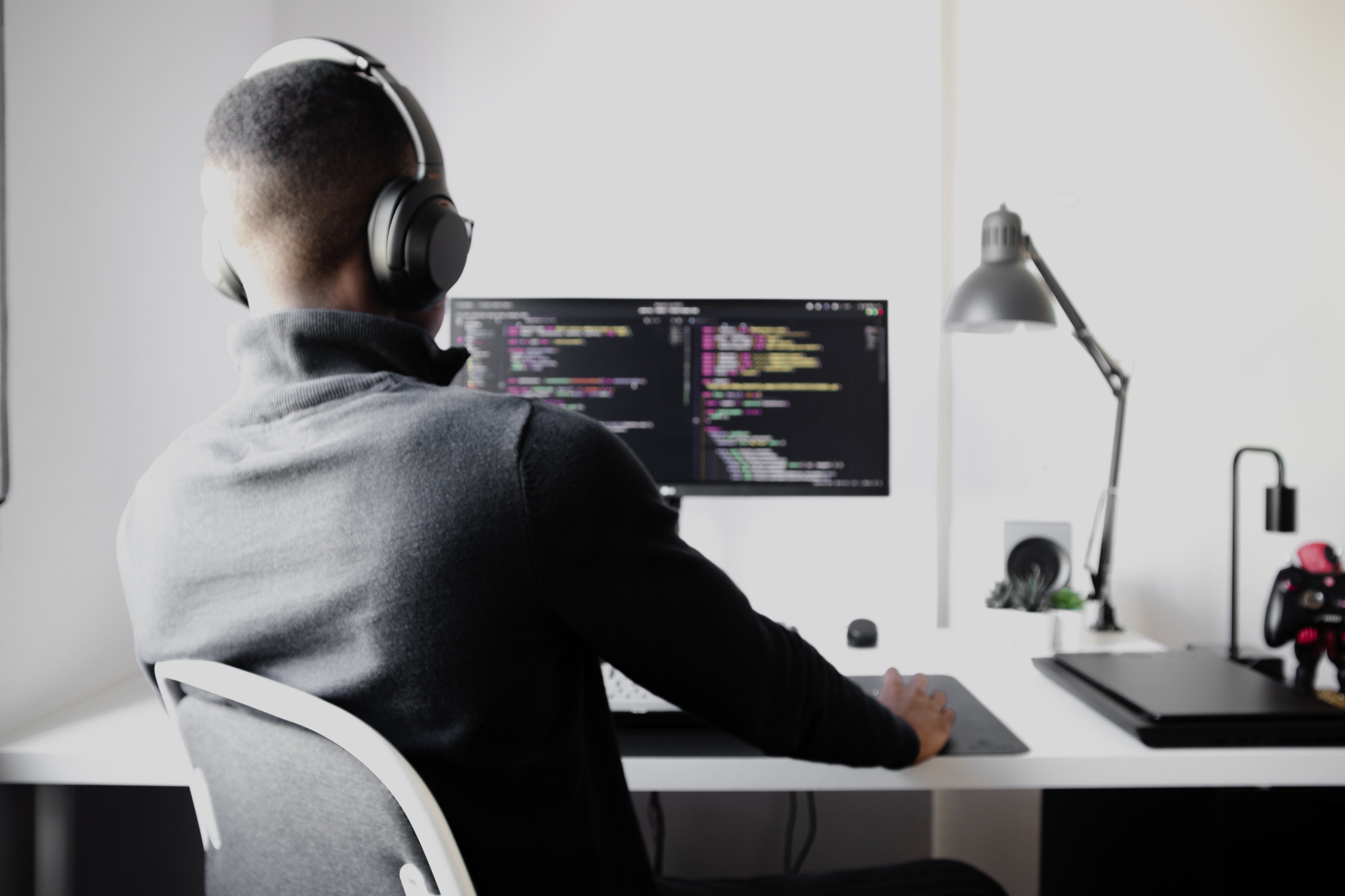 man wearing black headphones inputting JavaScript code on a computer
